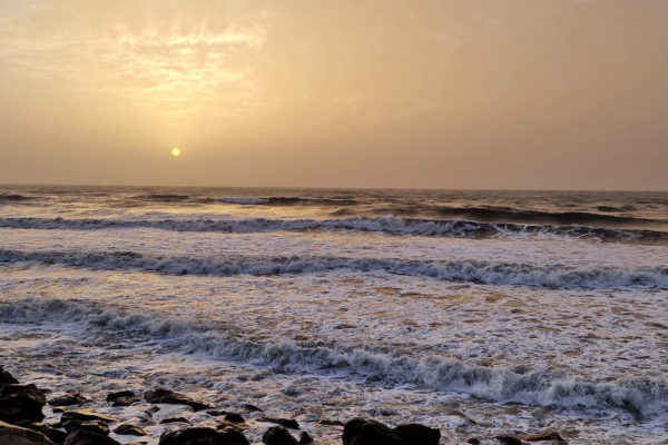 gulaktig solnedgång över hav med vågor