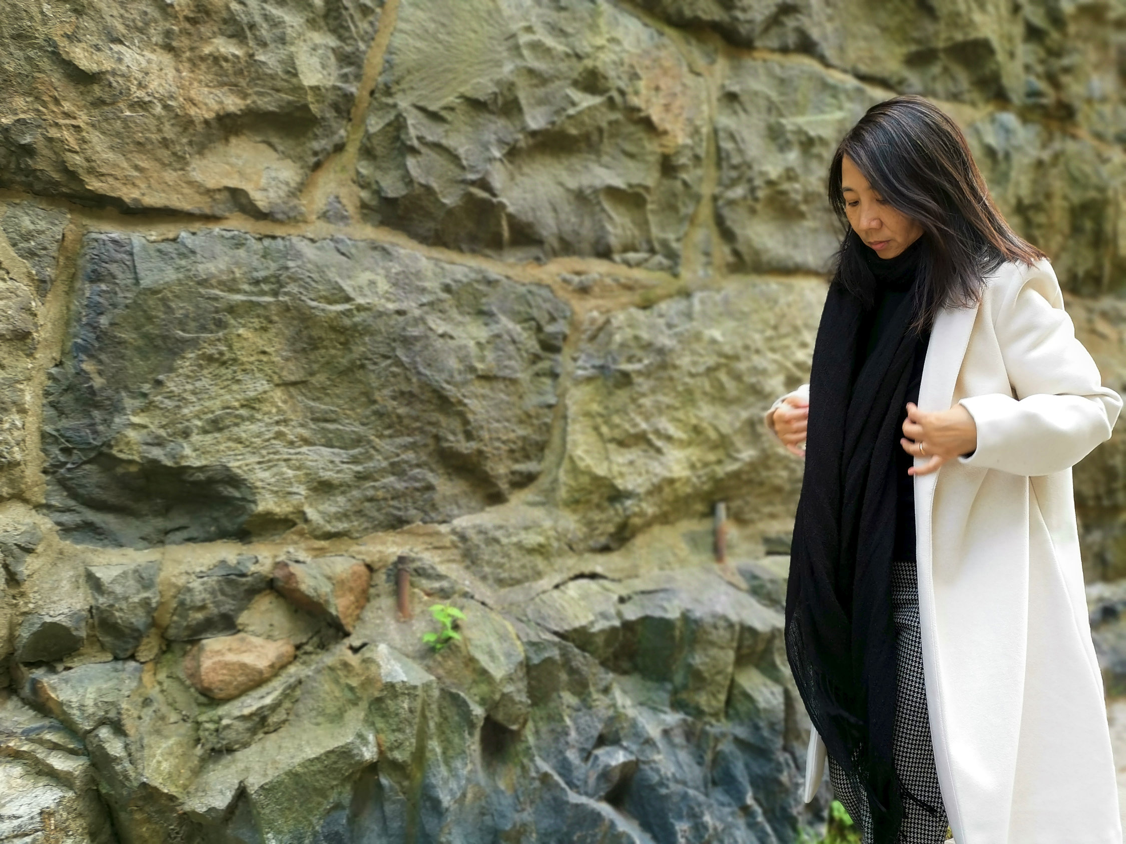En kvinna framför en stenmur.