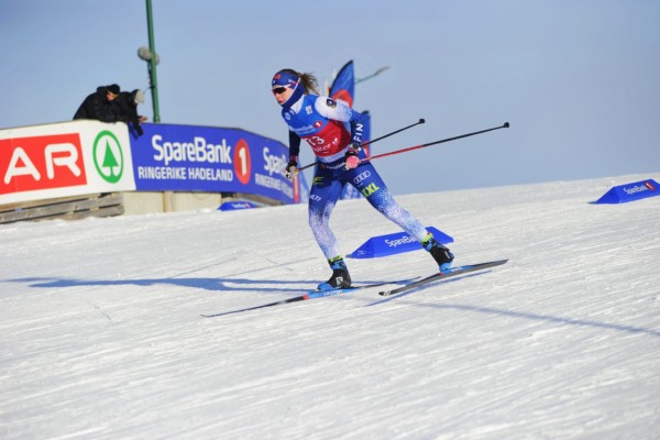En ung kvinna på skidor i en tävling.