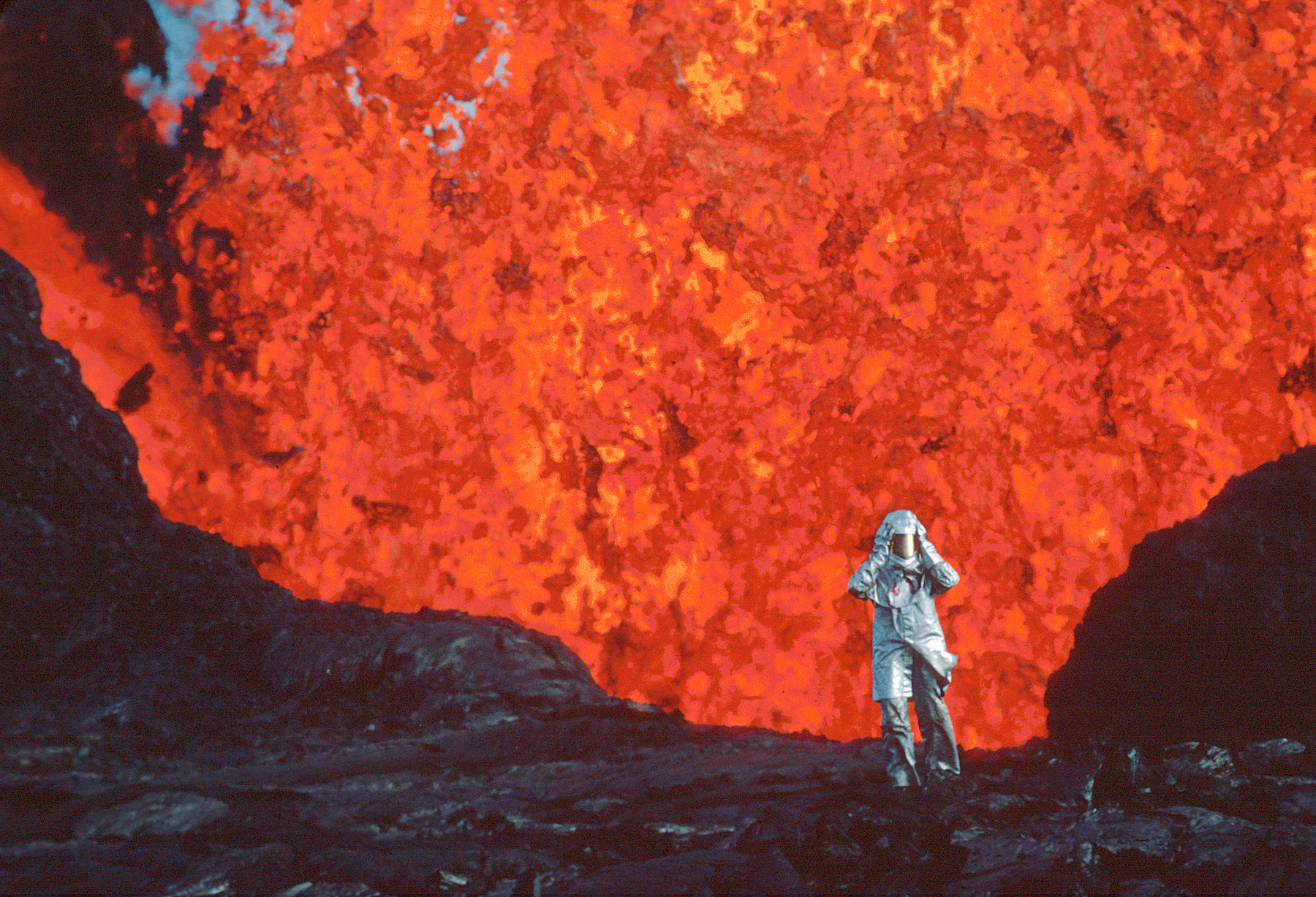 Katia Krafft wearing aluminized suit standing near lava burst at Krafla Volcano, Iceland.
