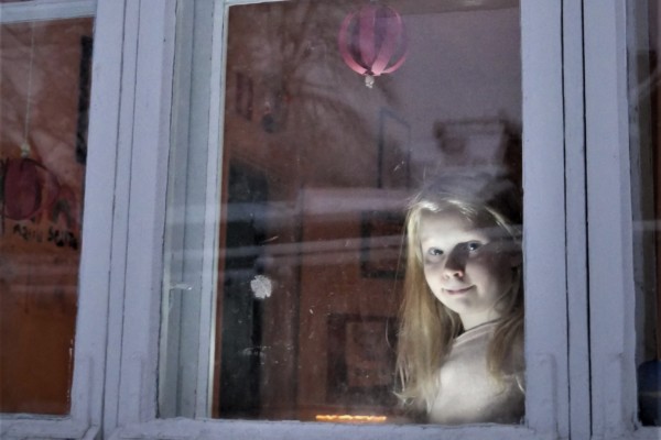 flicka i mörkt fönster