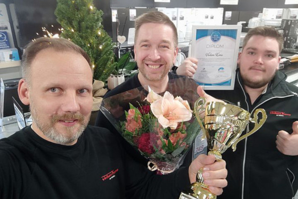 tre glada män med en pokal, blommor och ett diplom