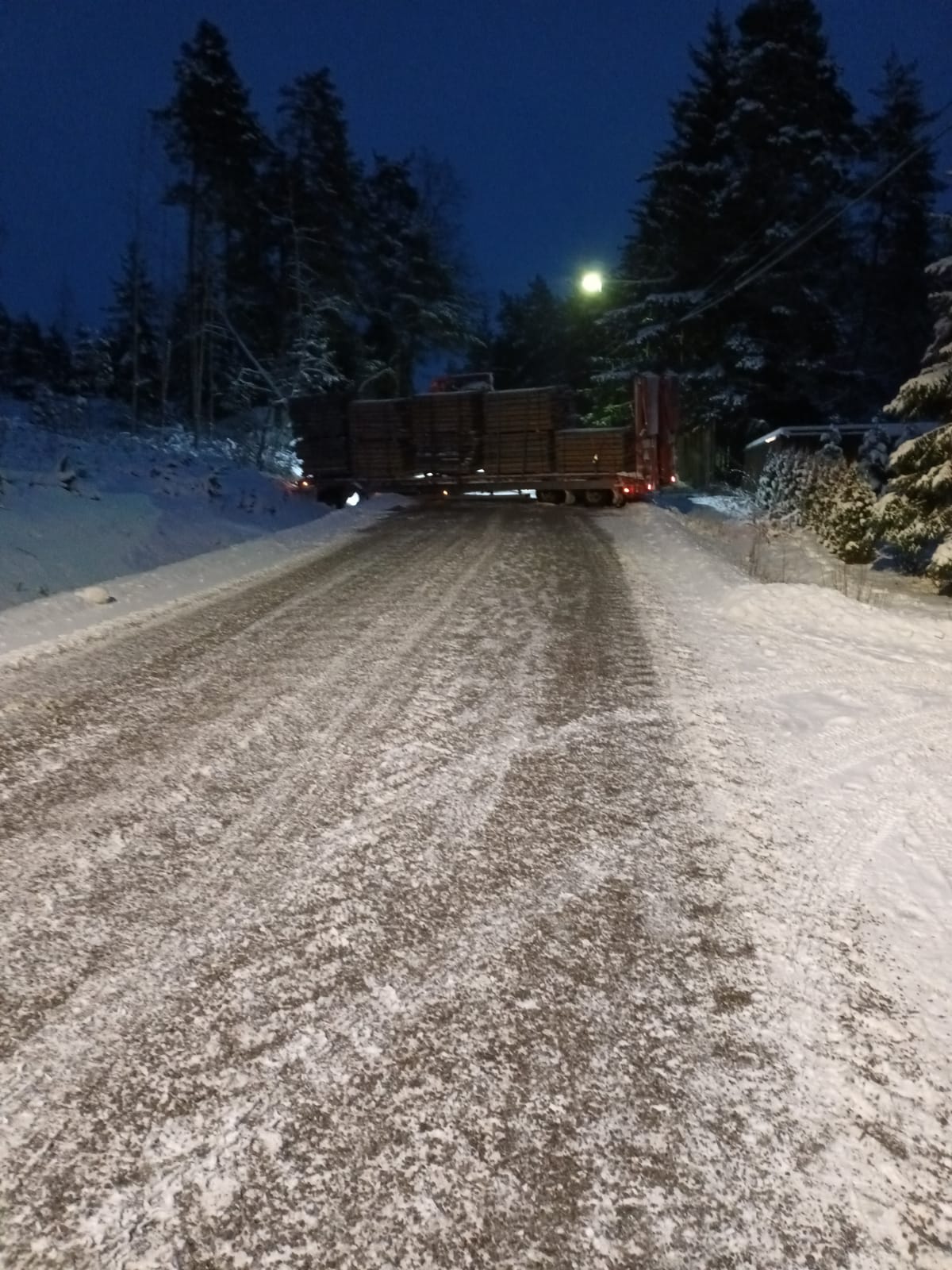 En långtradare tvärs över en väg på en snöig väg. 