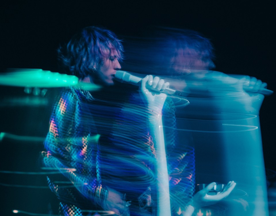 Artistbild i blått sken på en gitarrspelande sångare.
