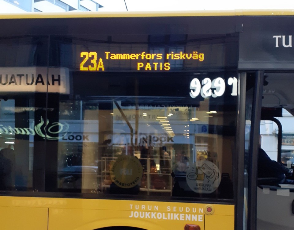 närbild av gul bussdörr som speglar sig i fönster