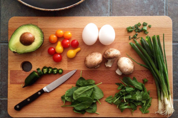 ett skärbräde med färska grönsaker och en kniv