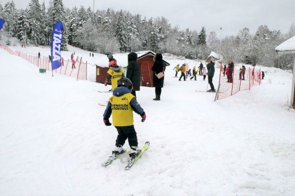 Barn på skidor i slutet av en backe.