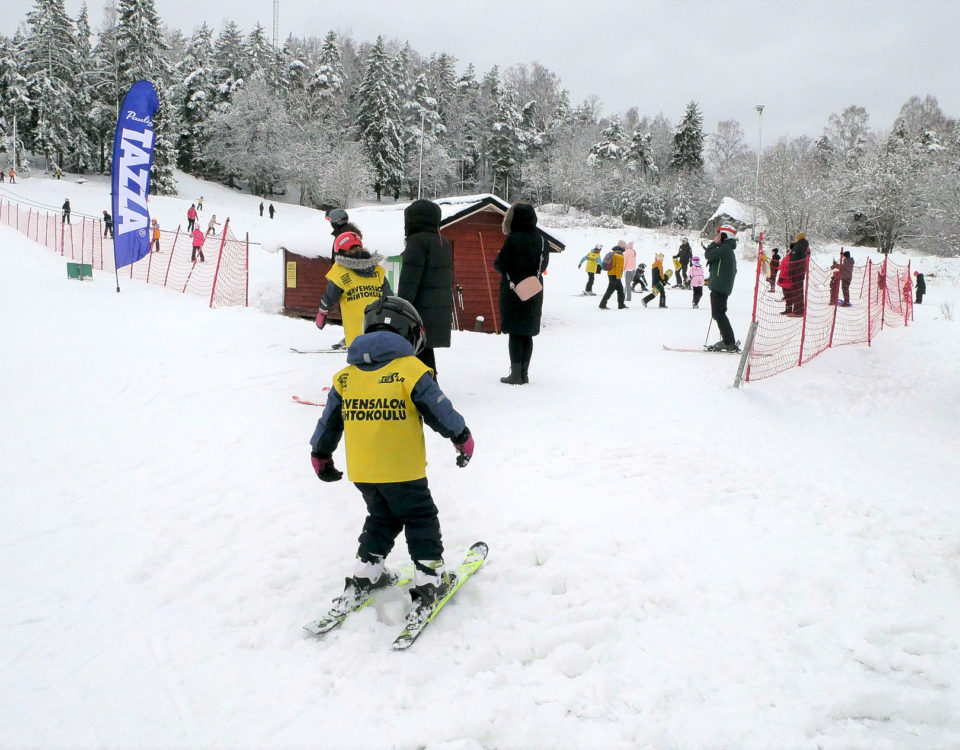 Barn på skidor i slutet av en backe.