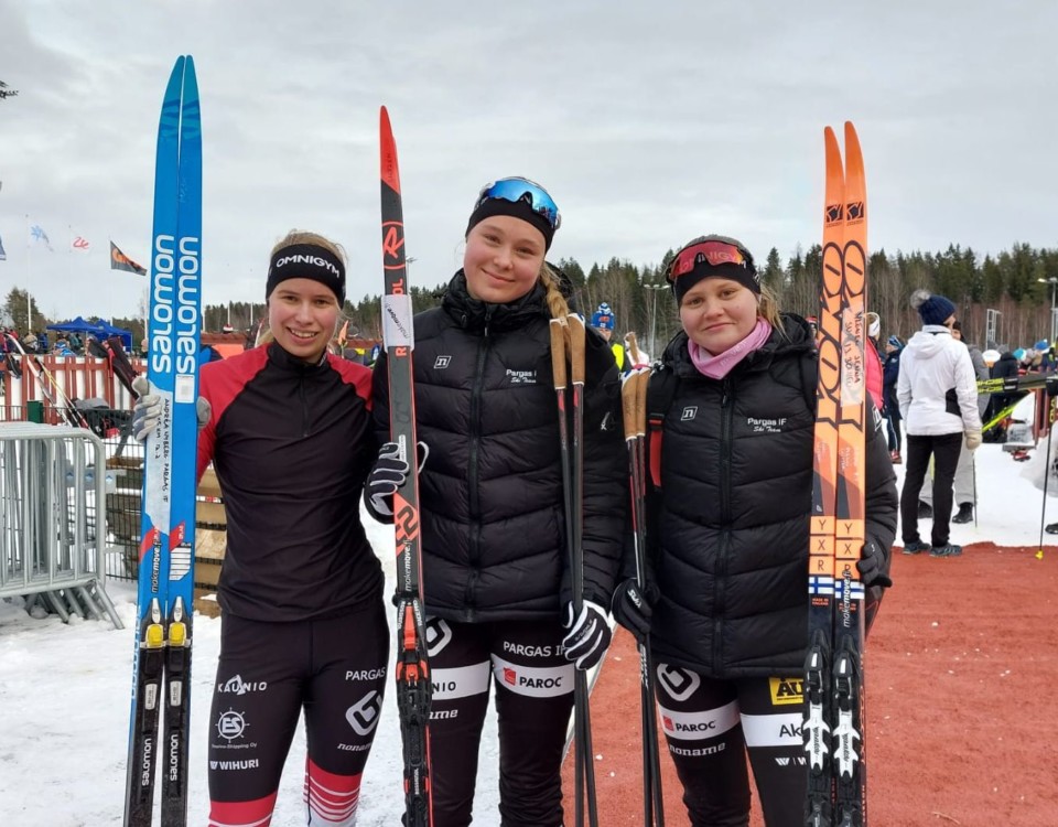 Tre unga kvinnor med skidor.