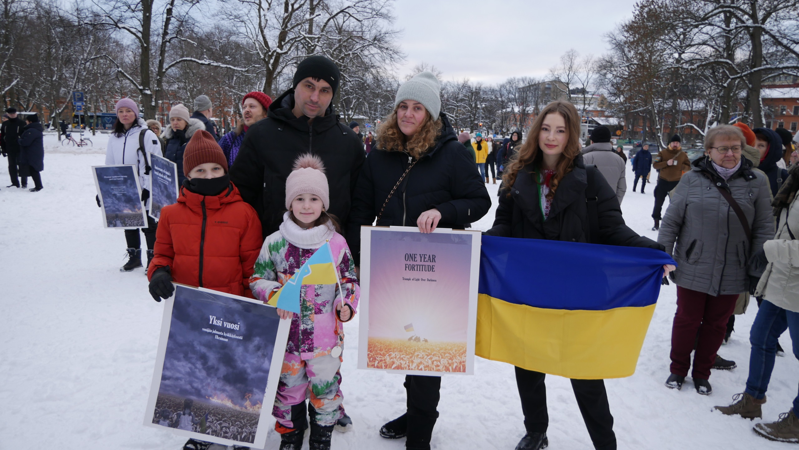 Familj med skyltar och ukrainsk flagga.