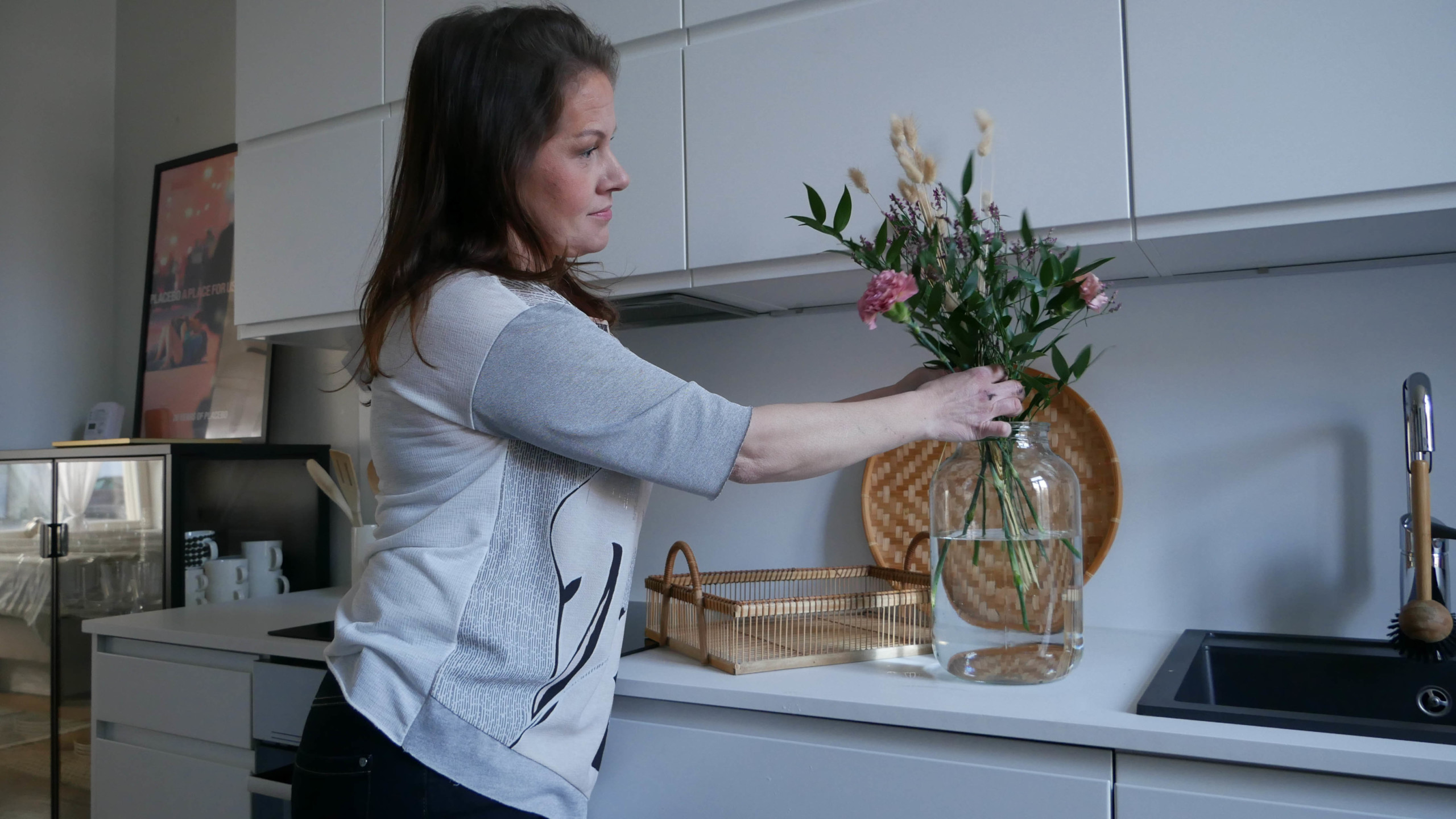 en kvinna sätter blommor i en vas