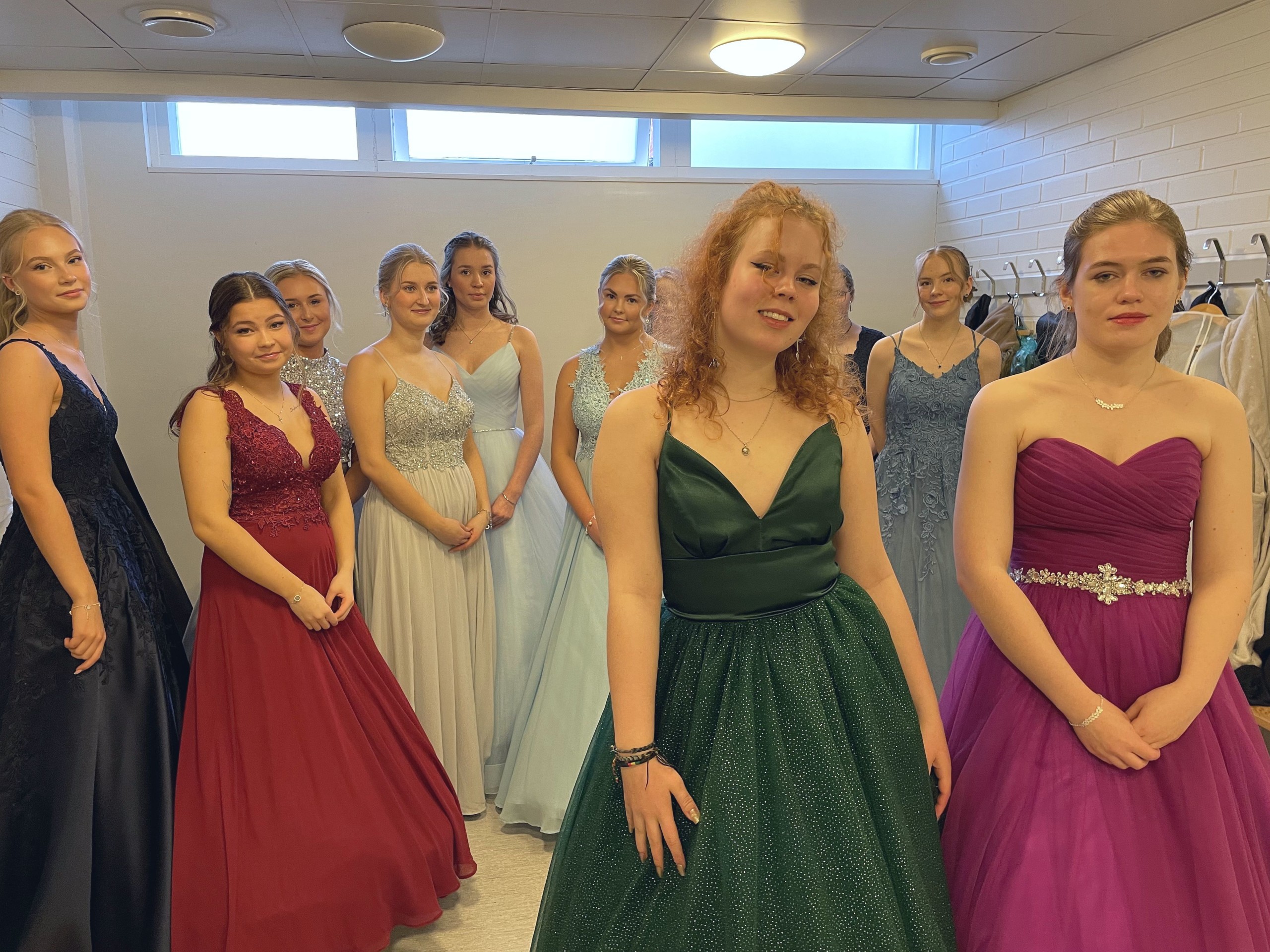 flickor i fina klänningar i ett omklädningsrum.
