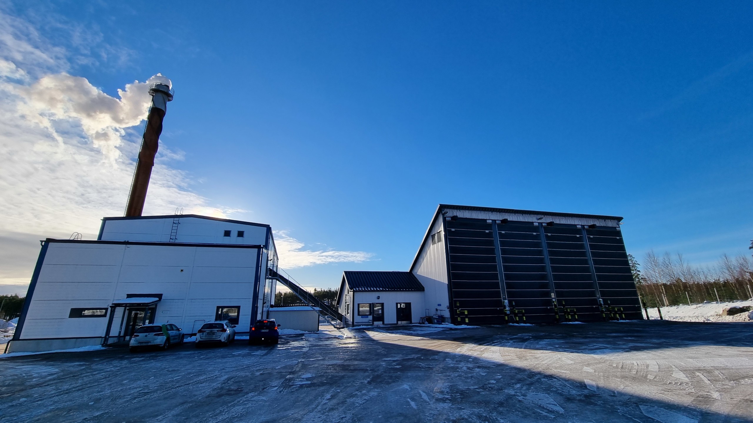 Biovärmecentral ryker mot blå himmel.