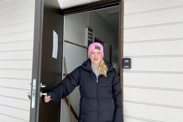 dam i vinterkläder öppnar dörren till ett hus
