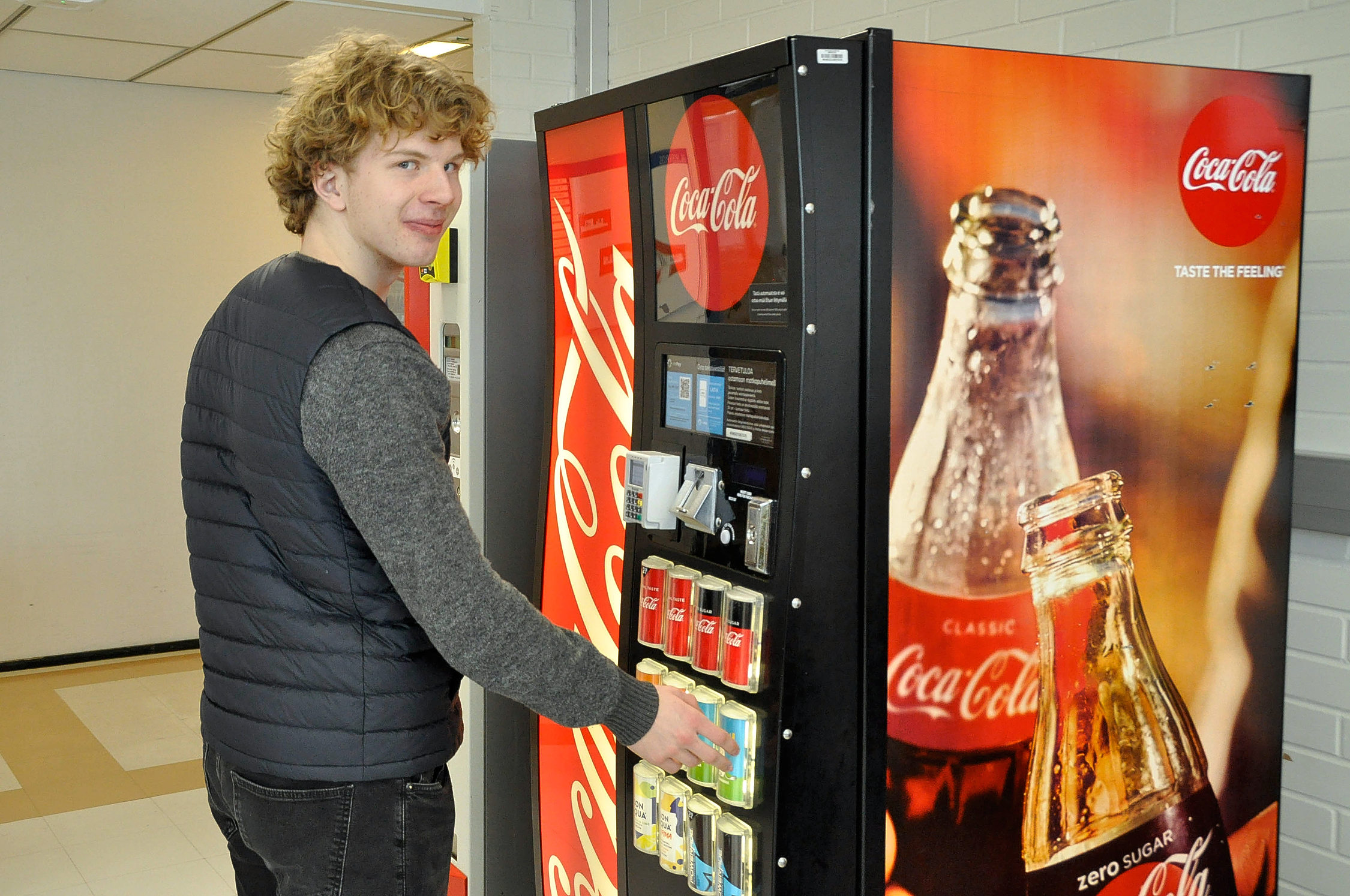 en pojke står vid en drickaautomat