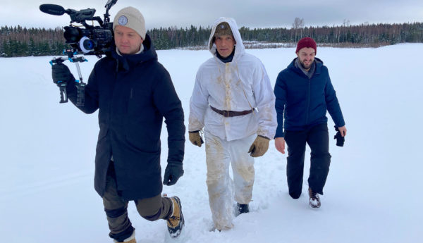 Tre män på snöig åker.