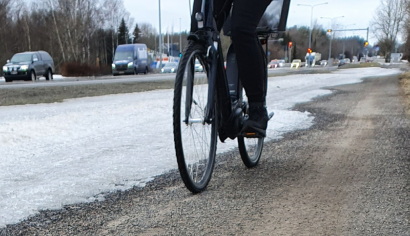 En person som cyklar på en cykelväg med grus.