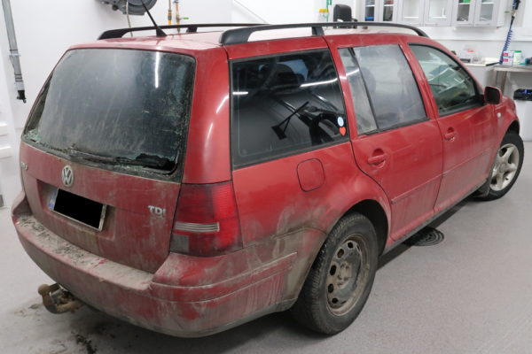 Sliten röd VW Golf i polisens förvar.
