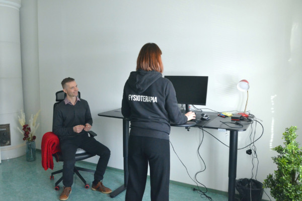 en man sitter i en stol och en kvinna står vid en dator