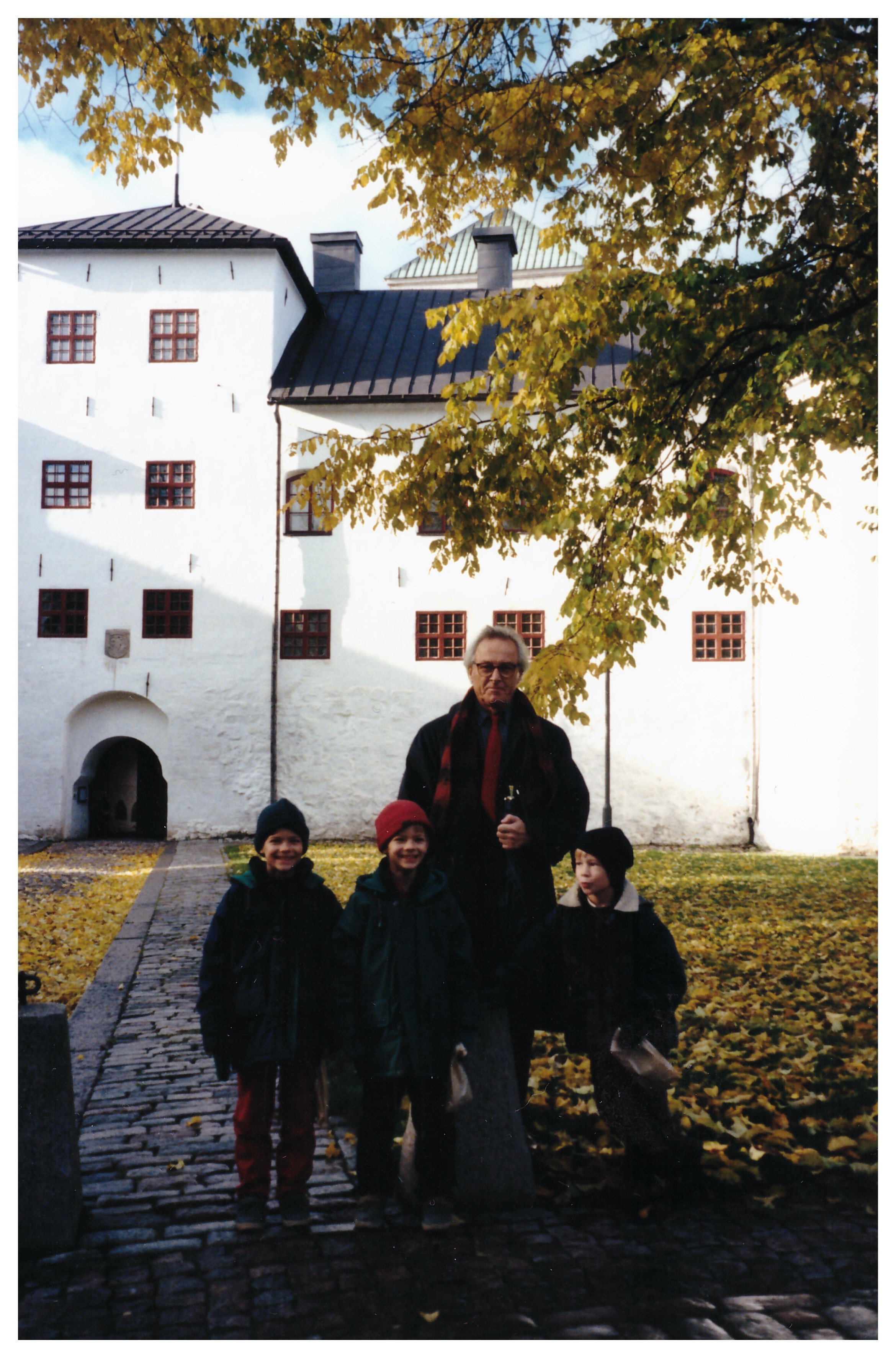 en äldre man och tre barn framför Åbo slott