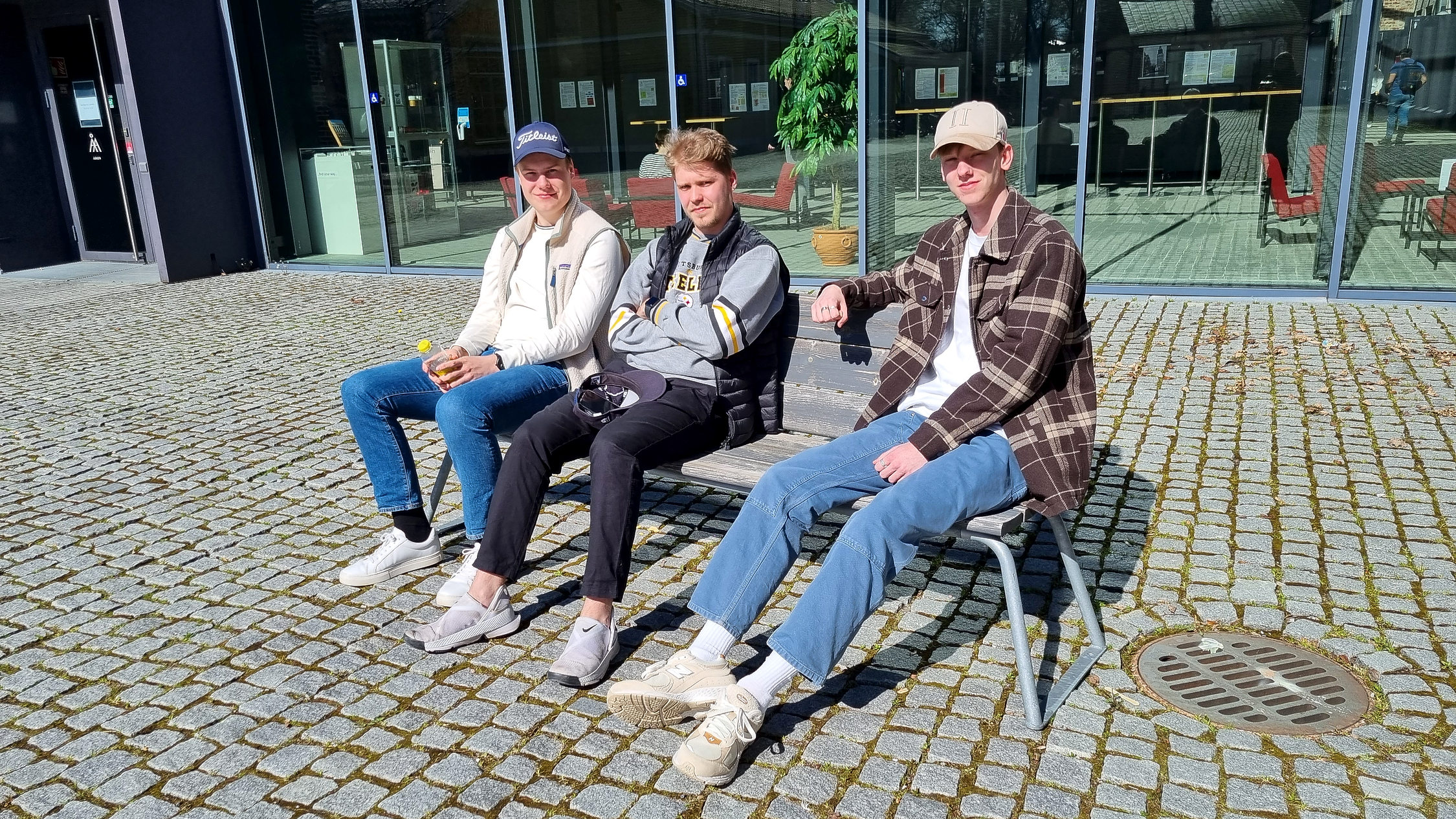tre unga män på en bänk i vårsolen