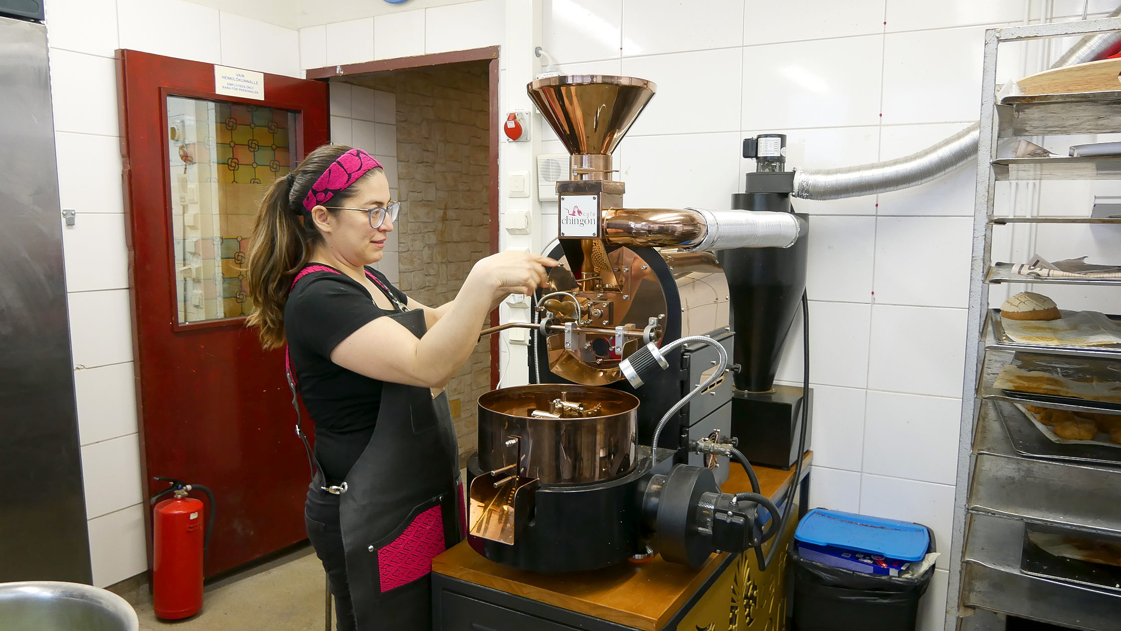 Kvinna står framför maskin som rostar kaffebönor.