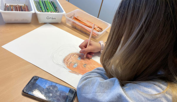 flicka som färglägger ett ansikte på ett papper