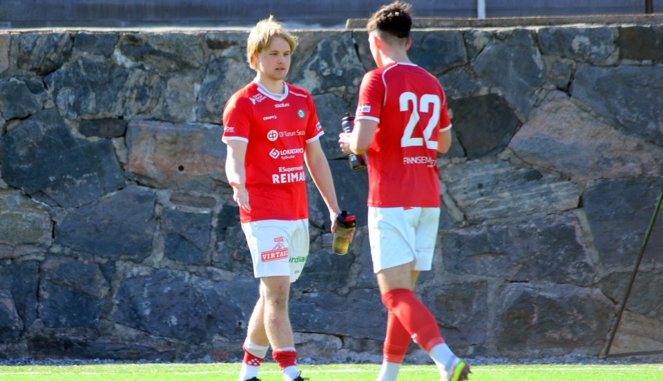 två fotbollsspelare i röda tröjor på en konstgräsplan