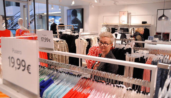 en kvinna står bakom ett klädräcke i en affär