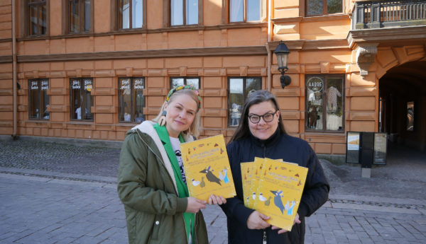 Två personer håller upp barnbok framför Brinkala.
