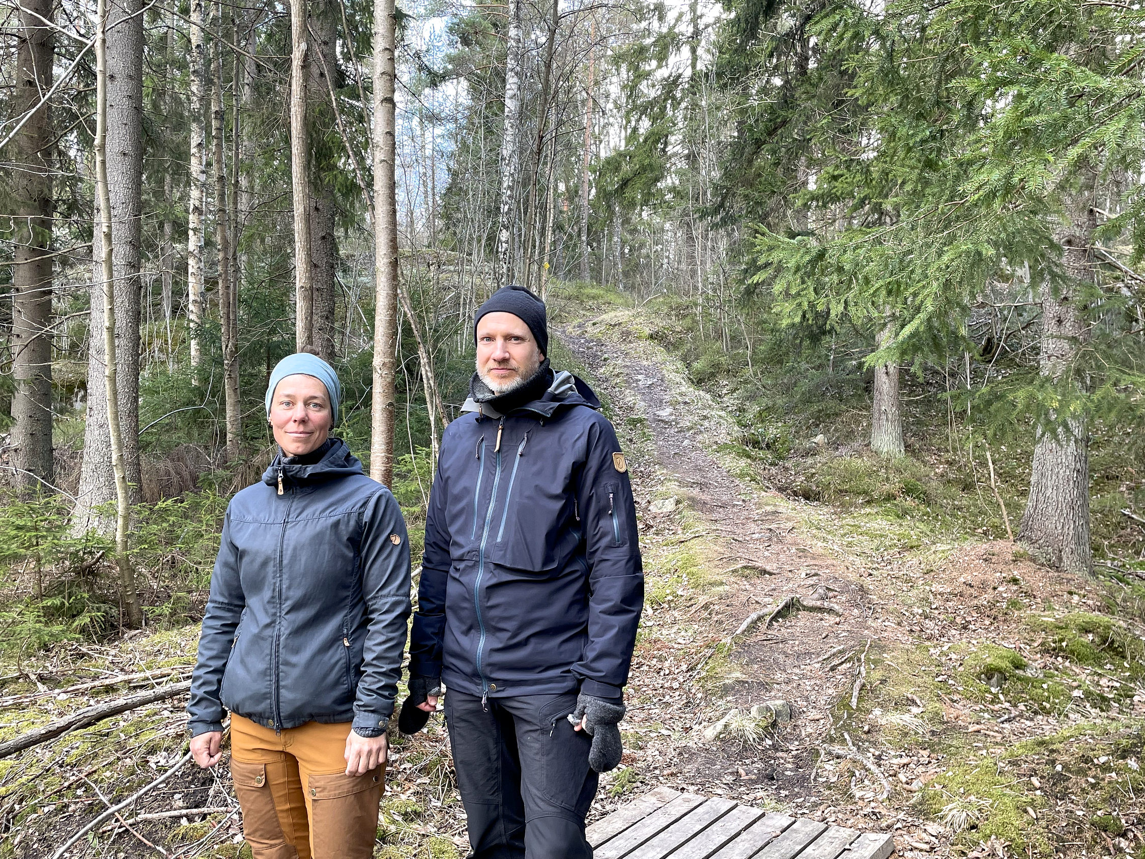 Två personer vid in stig som leder in i en skog