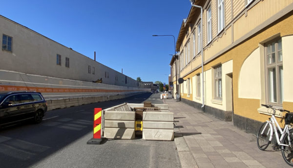 "Parklet"-uteservering med staket av betong bredvid väg och byggarbetsplats.