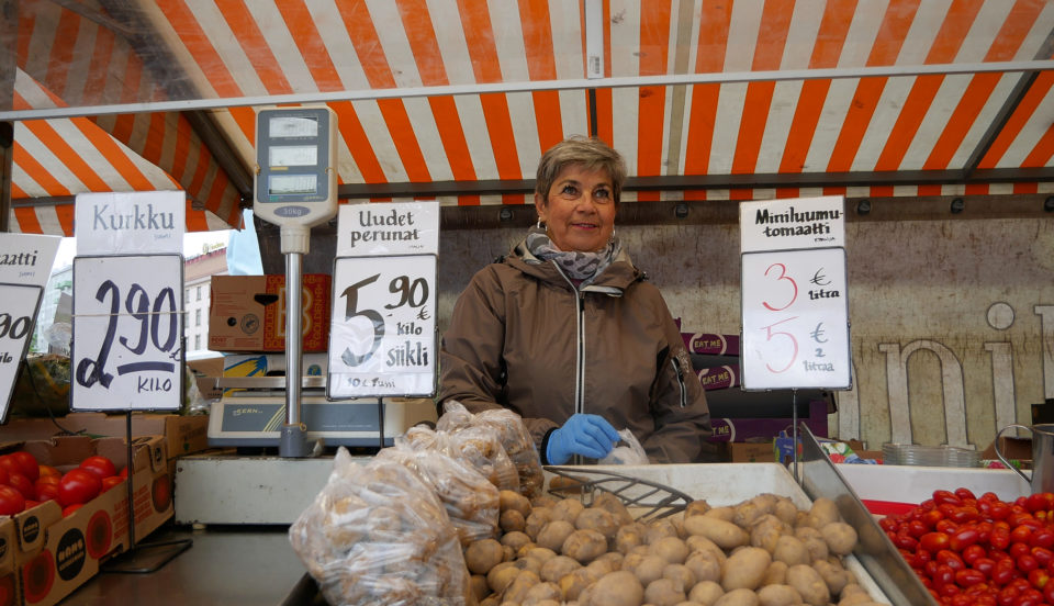 Torgförsäljare framför potatis de säljer.