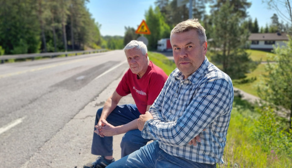Två män sitter vid landsväg.