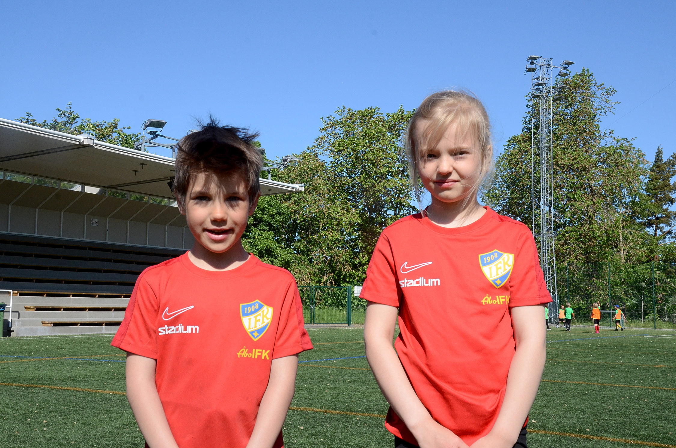 Två barn som deltar i ett idrottsläger står på en fotbollsplan.