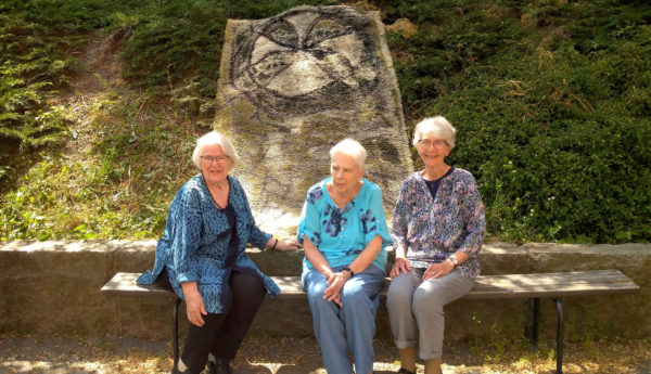 tre kvinnor sitter framför en vigselrya.