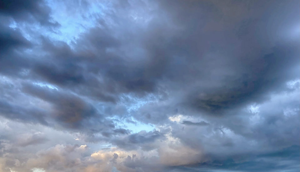 Bild på en himmel med regnmoln och lite kvällssol.