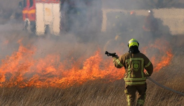 En brandman släcker en brand i terrängen.