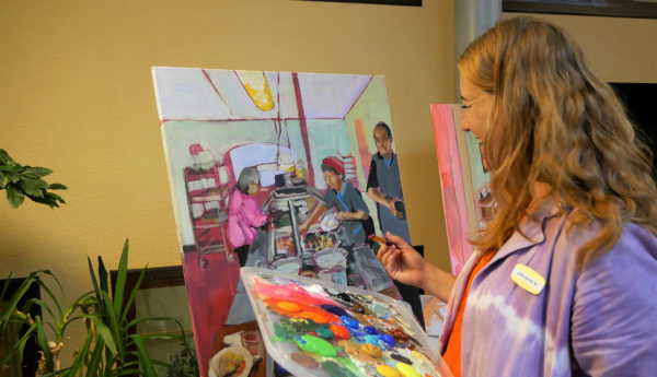 Kvinna som målar bild på människor med färgglada färger.