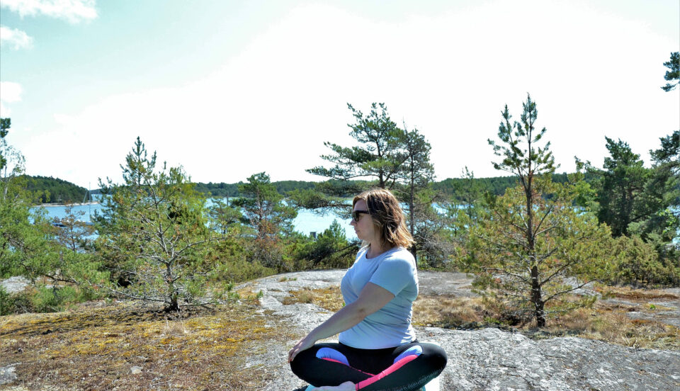 Nina Mya yogar på klippa.