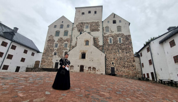 Kvinna i svart sammetsklääning på slottsgården utanför Åbo slott.