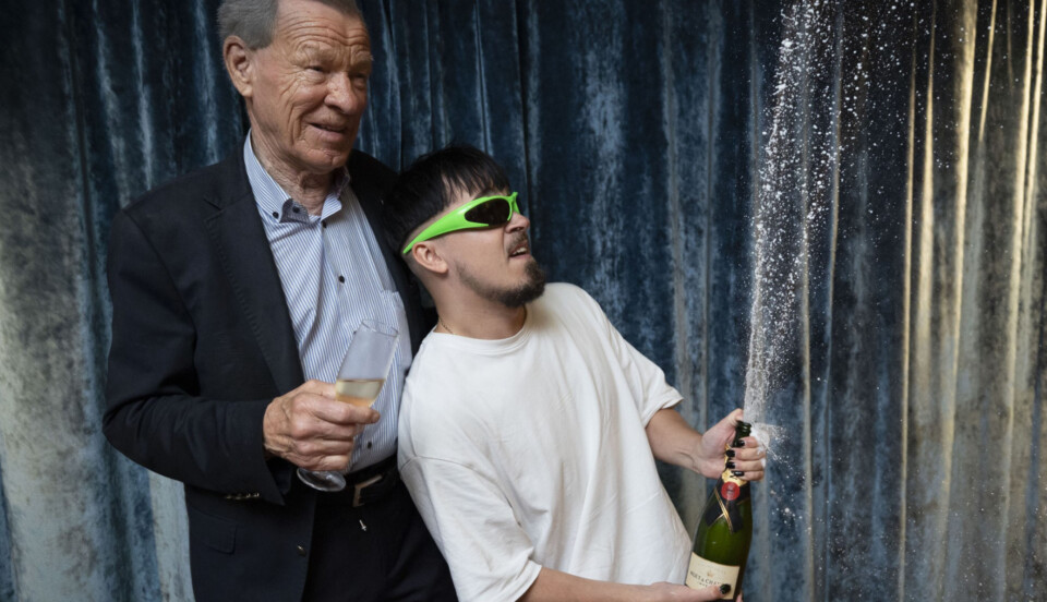 en man sprutar champagne medan en annan tittar på