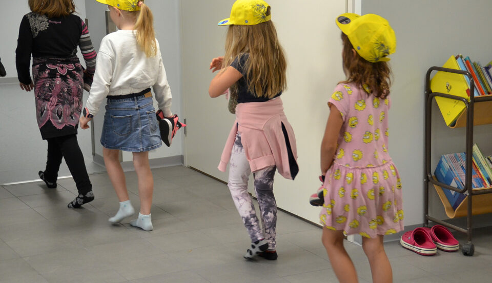 Barn i gula kepsar i en skolkorridor.