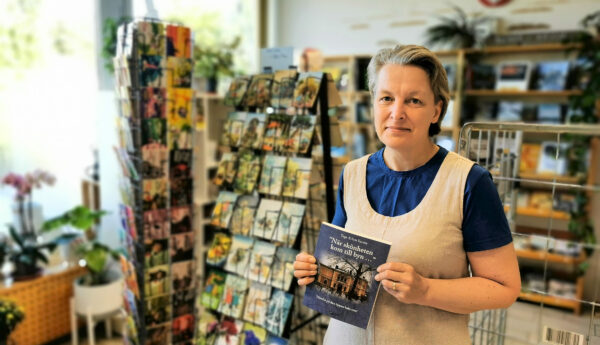 kvinna håller upp bok i butikslokal