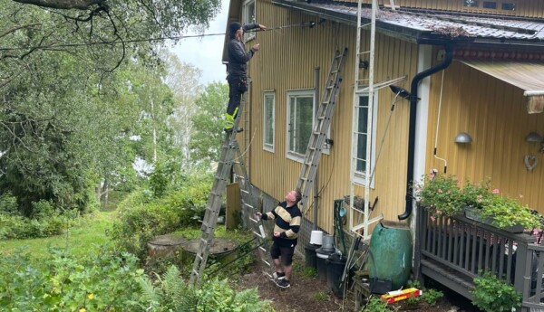Två män vid ett hus försöker reparera en kabel.