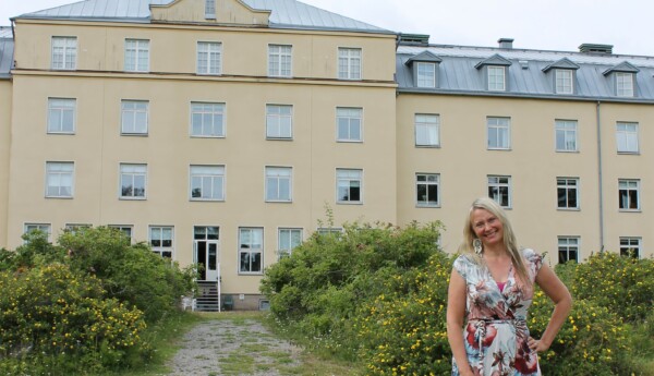 Kvinna står utanför ett stort gult hus i Knipnäs, Ekenäs.
