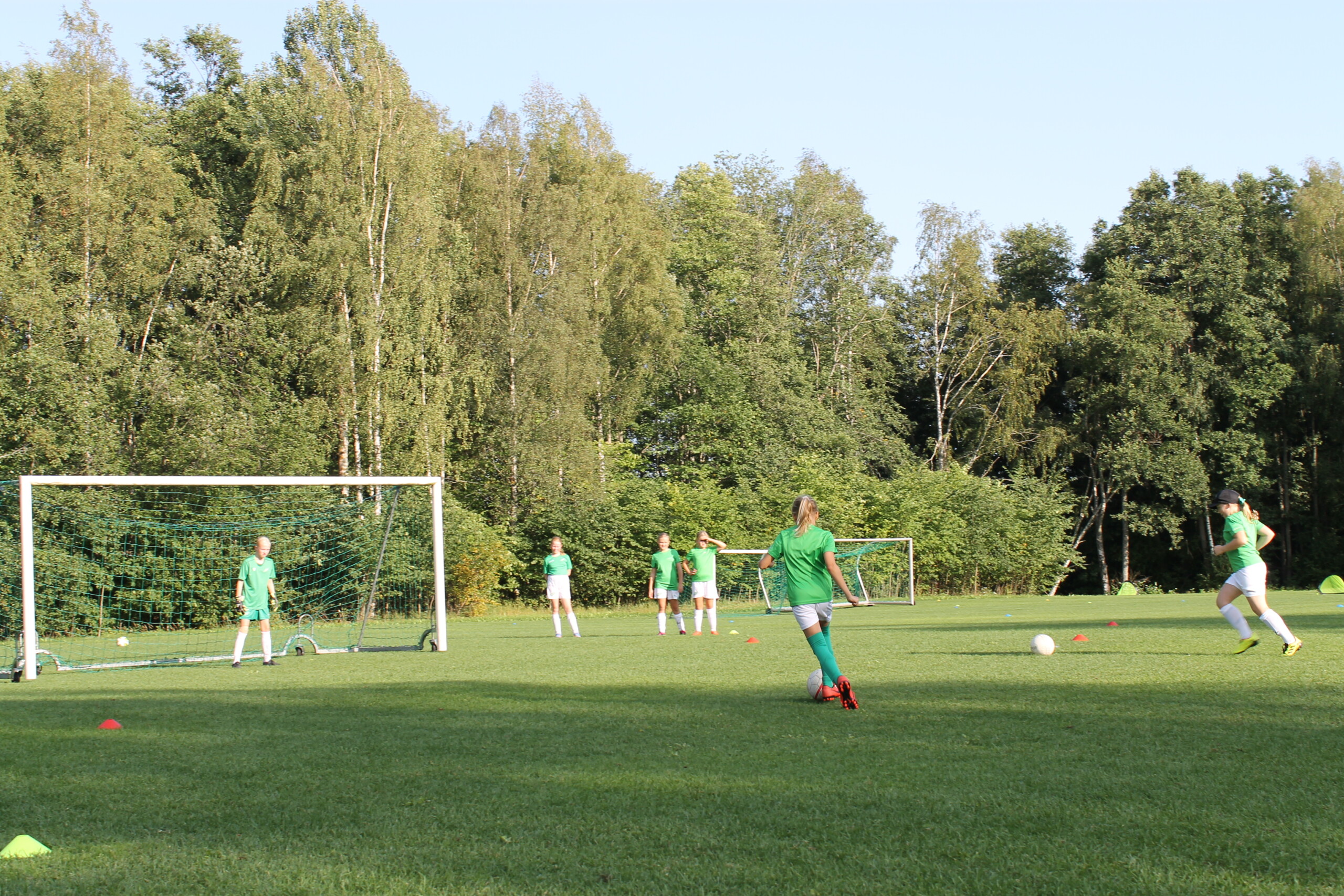 EIF:s flicklag med flickor födda 2012 och 2013 har en fotbollsträning utomhus på en gräsplan i Ekenäs. Flickorna övar på att skjuta mål.