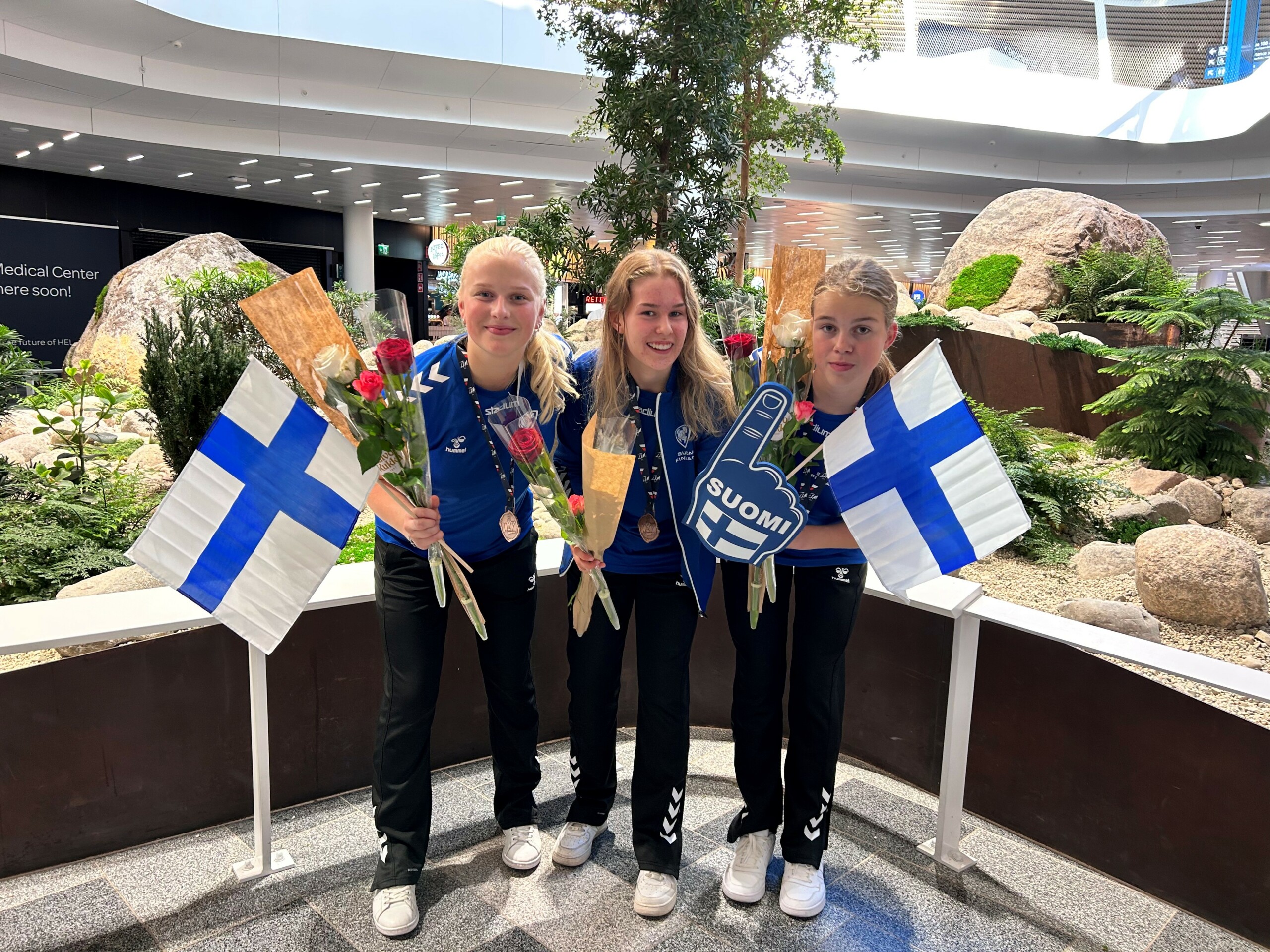tre tjejer med blommor och finska flaggor