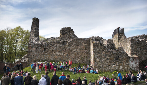 Stor folkgrupp vid ruinen av ett gammalt slott