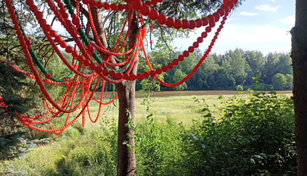 Ett konstverk av röda plastbollar i naturen.